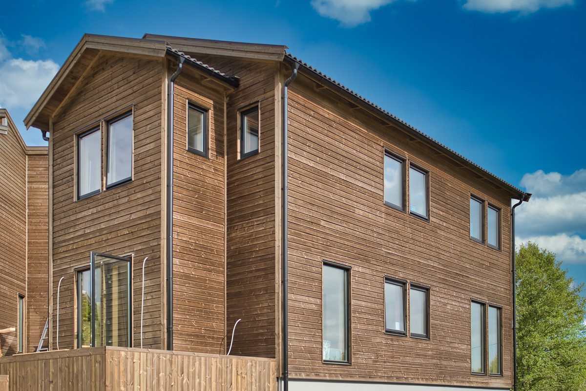 Hus med brun träpanel och stora fönster i flera våningar