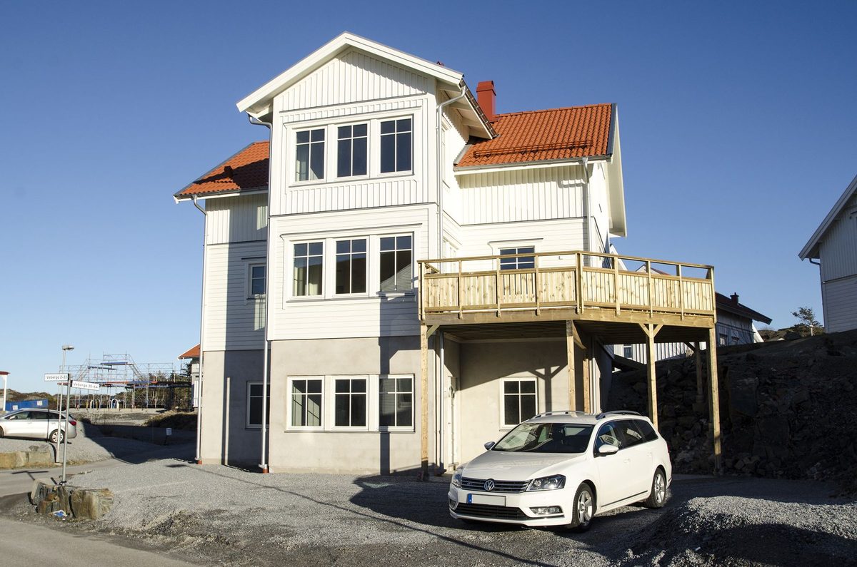 Vitt hus i tre plan med rött tegeltak, putsad bottenvåning och balkong på stolpar, Veberga